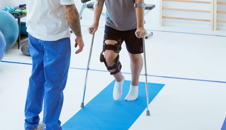 man wearing knee brace using crutches