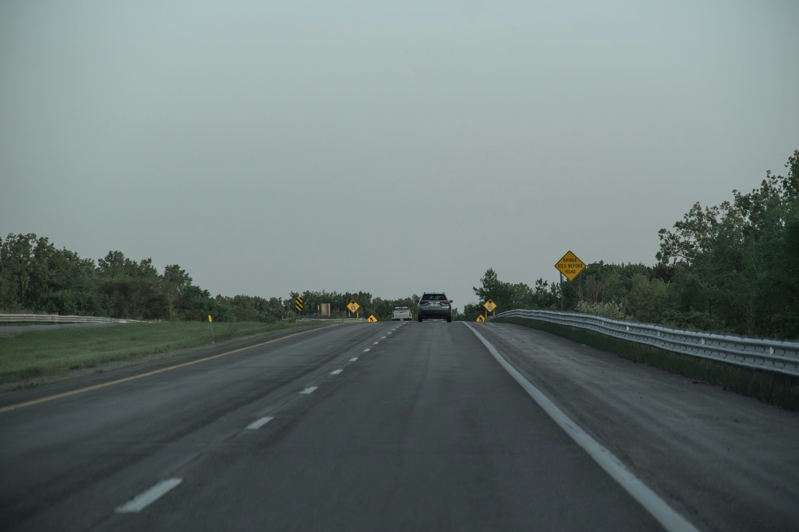 a highway at dusk with few cars on it