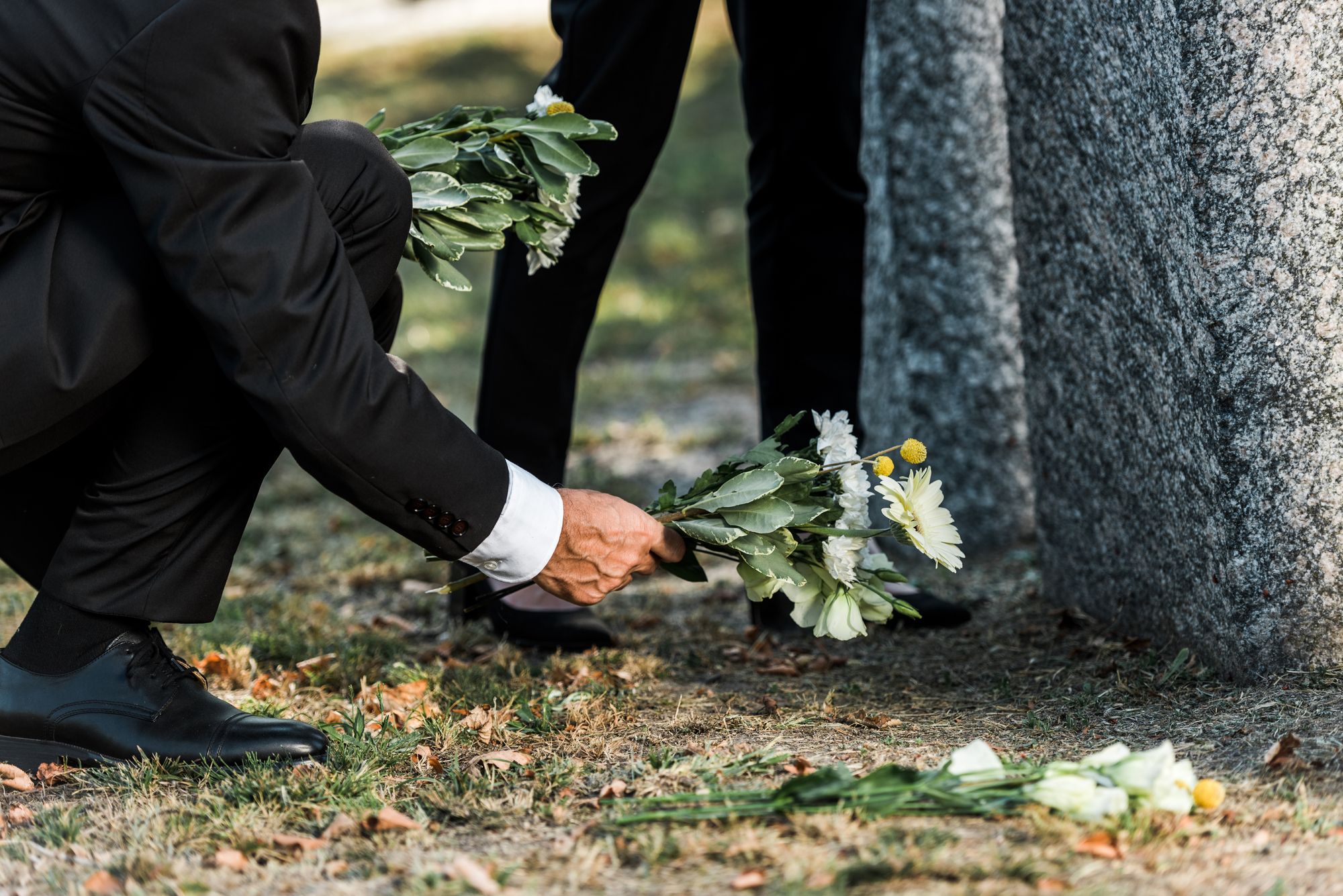 Old man putting a flower on the grave