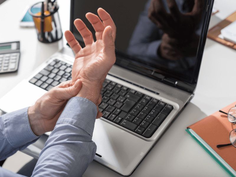 Man holding wrist from pain caused by computer work