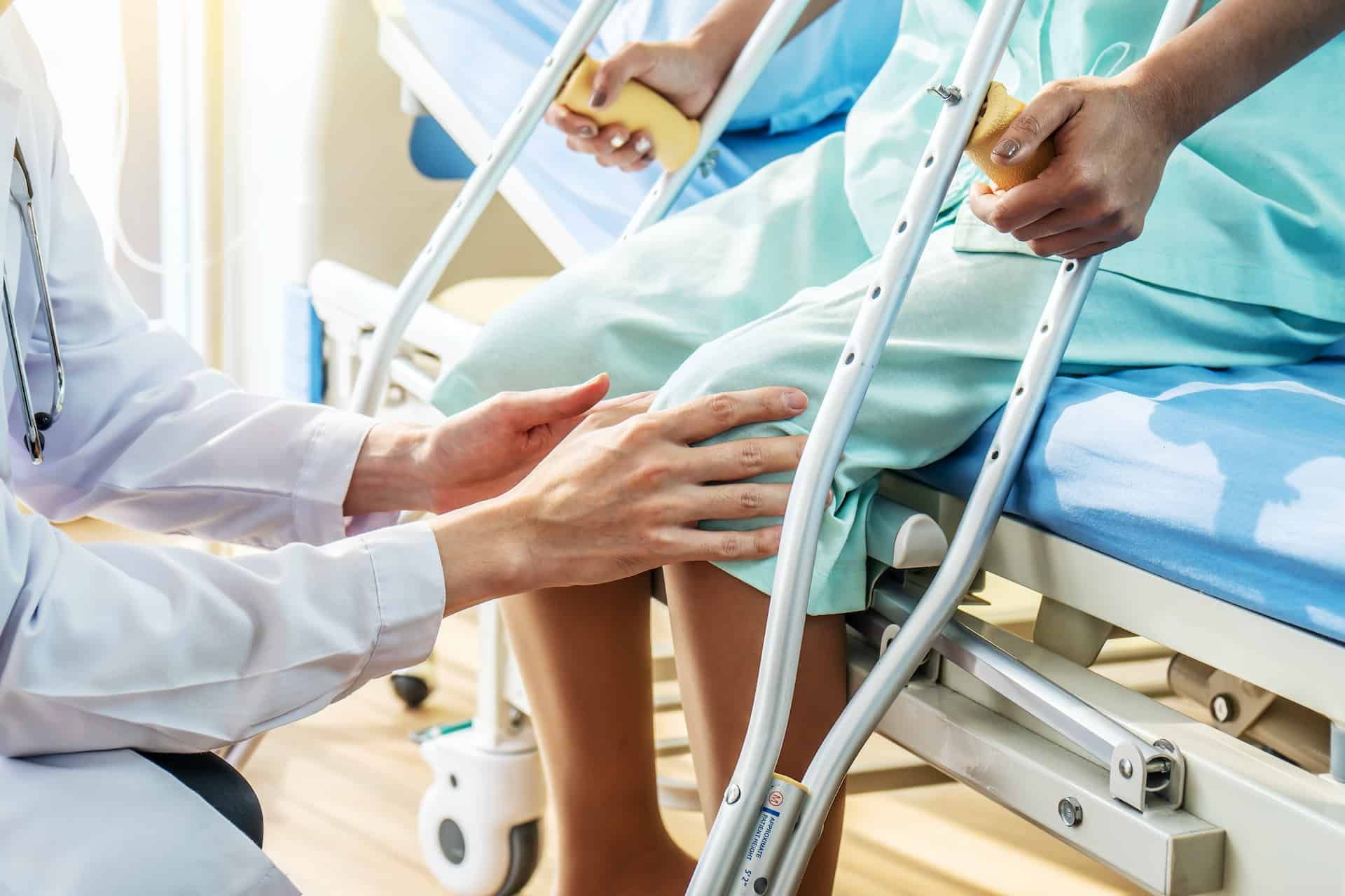 Close-up of Doctor examining female patient with injured leg or knee in clinic