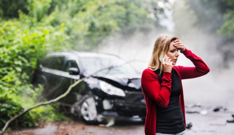 woman on phone in front of car