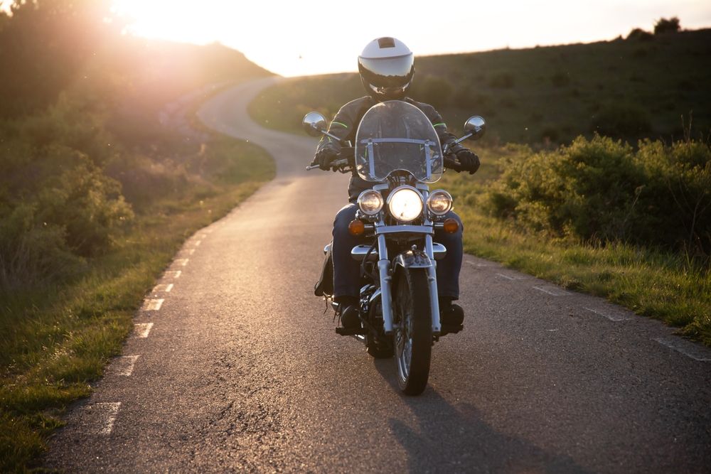 Motorcyclist in a helmet riding on a country road at sunset