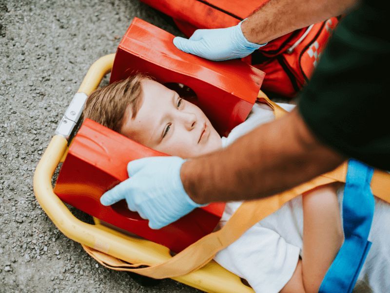 young child laying on a paramedic gurney with head immobilizer
