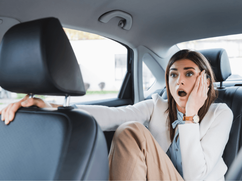 Woman looking surprised in a car's backseat