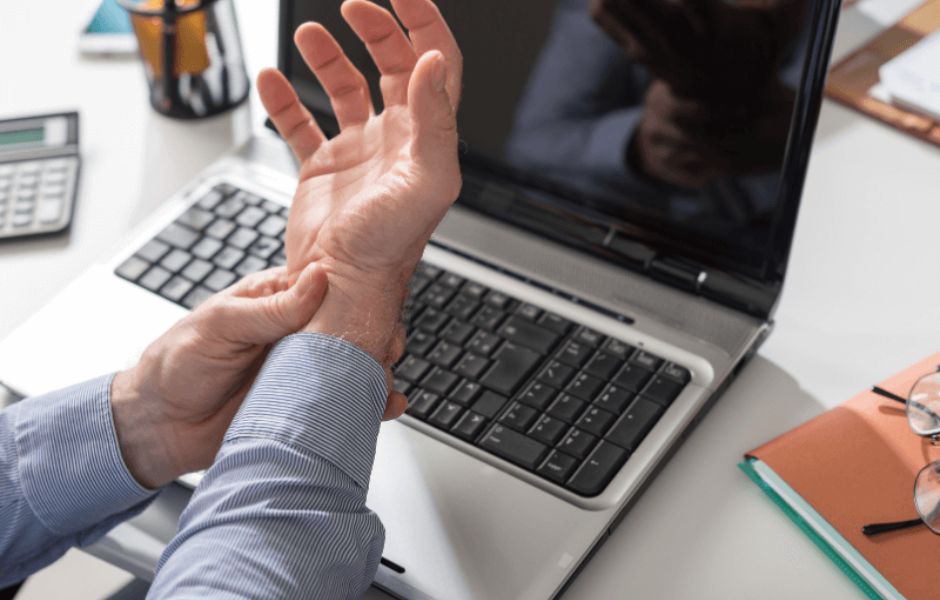 Man holding wrist from Carpal Tunnel caused by his computer work