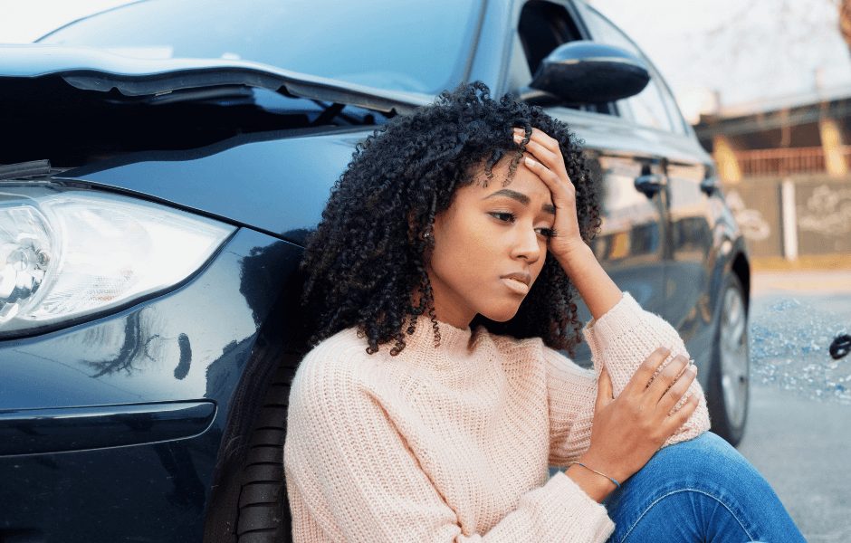 woman sitting against a car accident