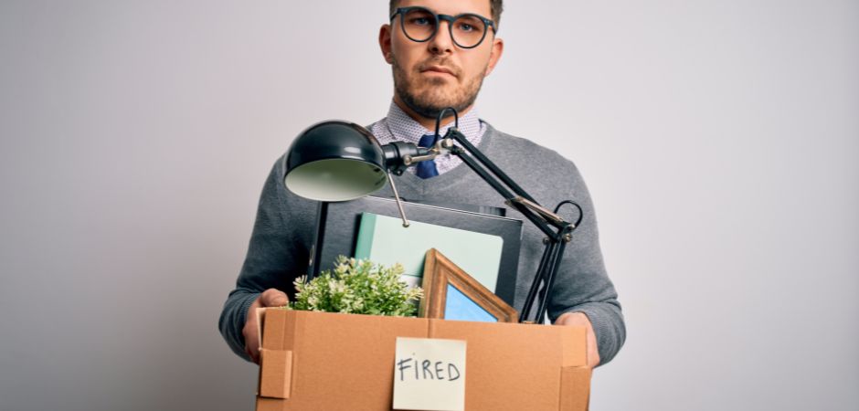 Man just fired from job holding a cardboard box with his belongings in it