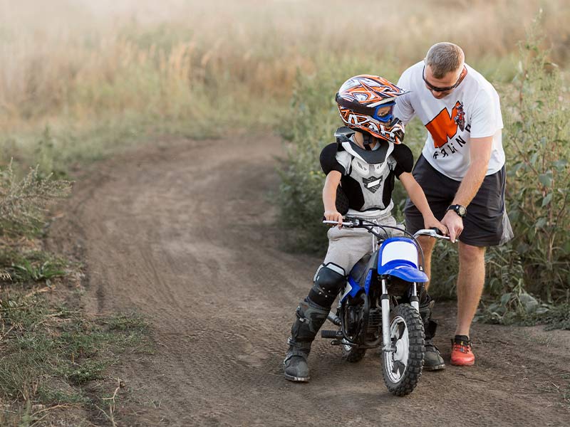 A dad teaching his son how to ride a dirtbike