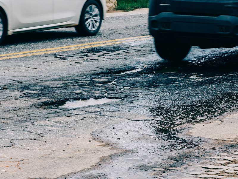 car driving through a pothole in the road