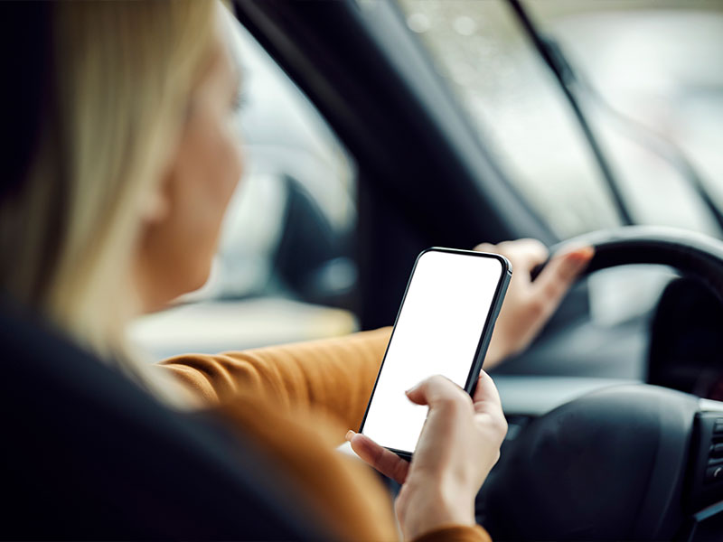 woman driving while looking at her phone