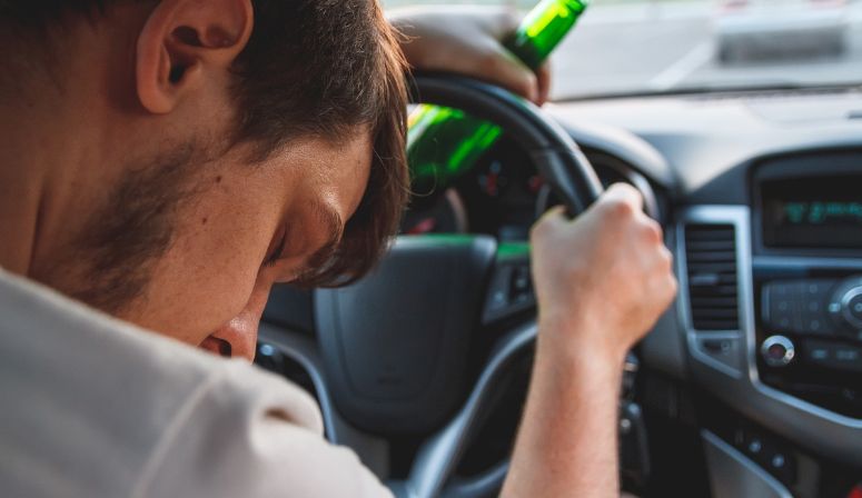 man in car holding a beer bottle