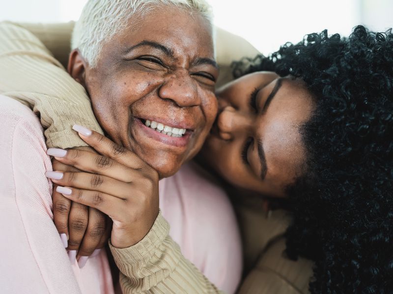 Elderly woman being hugged by her daughter