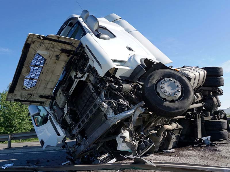 truck laying on the side of the road after an accident