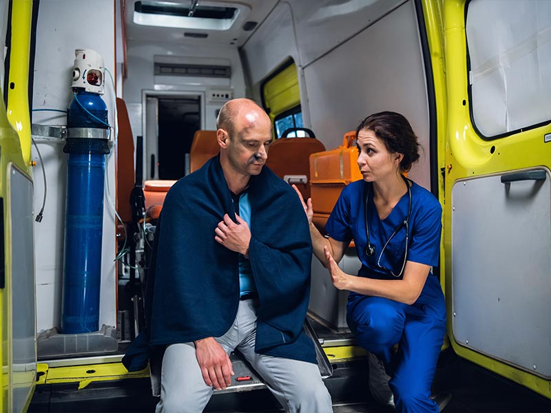 paramdeic talking to an injured man sitting in an ambulance
