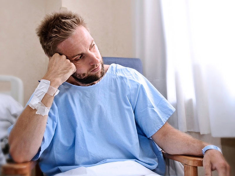 a man wearing a hospital gown looking out a window