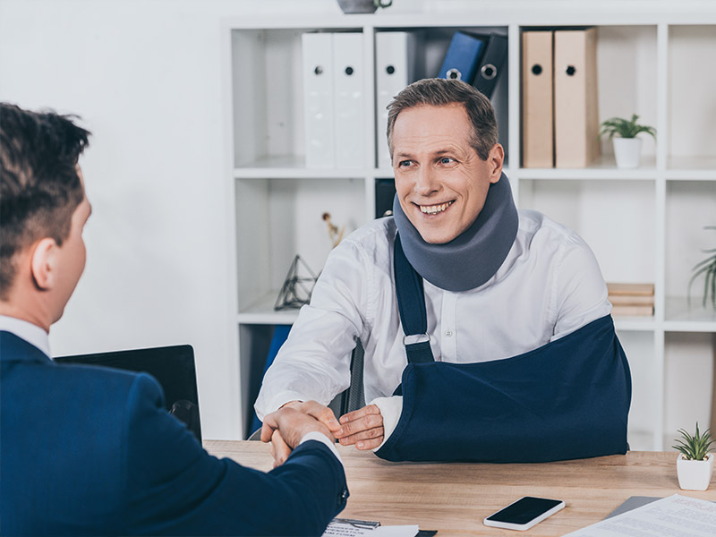 a man wearing a neck brace and an arm brace shaking hands with a lawyer