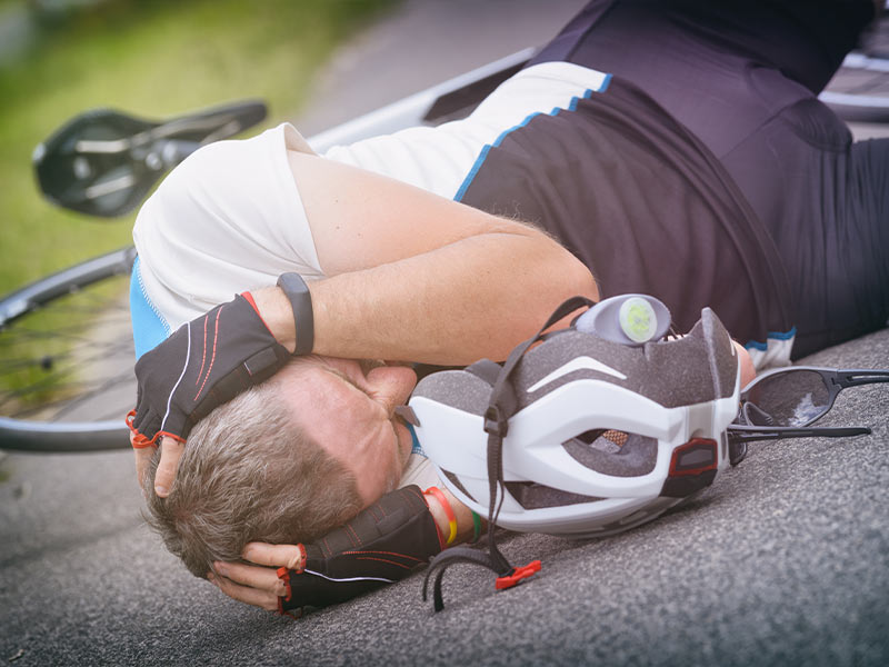 woman who fell off her bike holding her head in pain