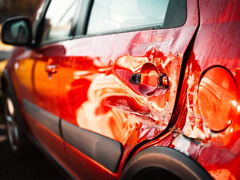 a red car with damage to the side of the vehicle