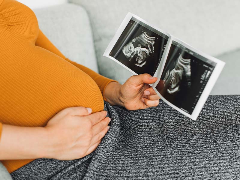 A pregnant woman looking at an ultrasound of her baby