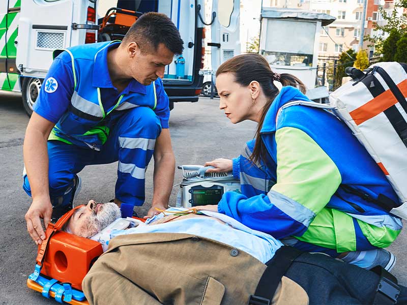 first responders performing life saving measures on an elderly man