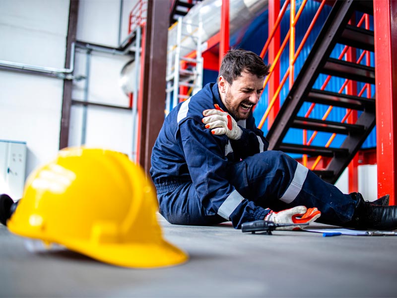 factory worker on the ground grabbing his shoulder in pain