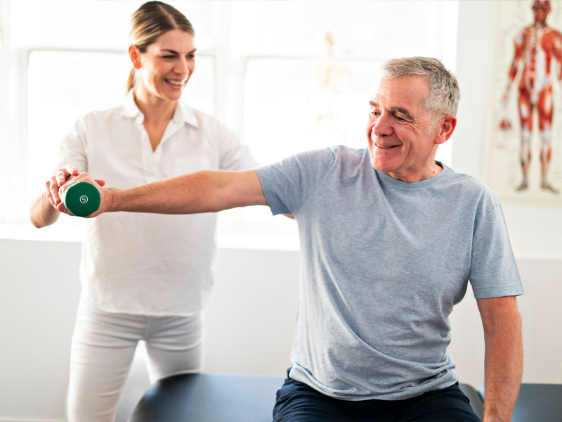 elderly man exercising his shoulder muscles with a physical therapy
