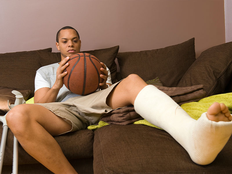 man with his leg in a cast sitting on a couch