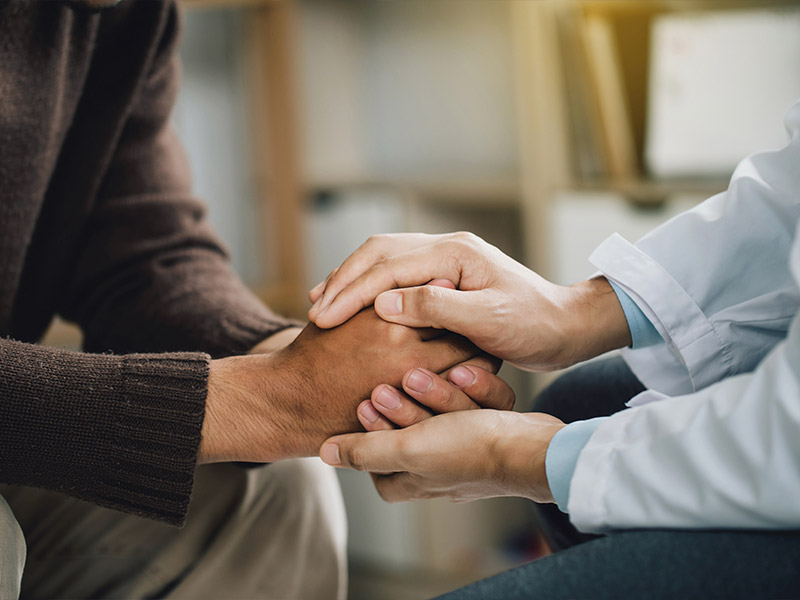 man sitting down holding hands with another man