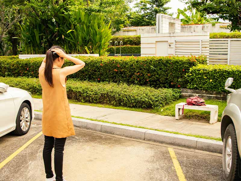 woman looking at an empty parking spot after her car was stolen