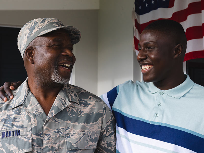 Airman standing next to his son smiling