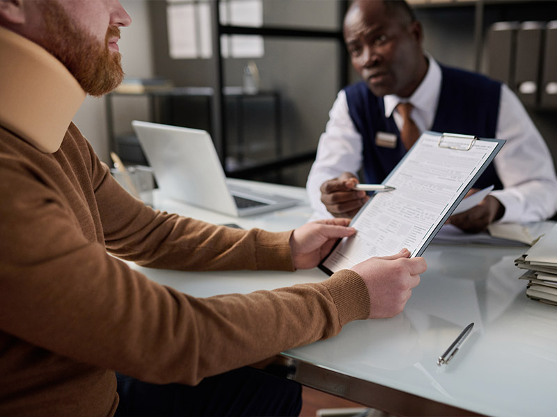 a man wearing a neck brace looking at paperwork 