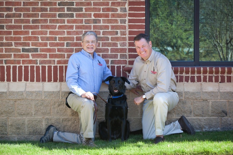 Bill Brightman with SD4V and John Hawkins, Owner and Founder of the Hawkins Law Firm pose with Darla, a service dog in training.