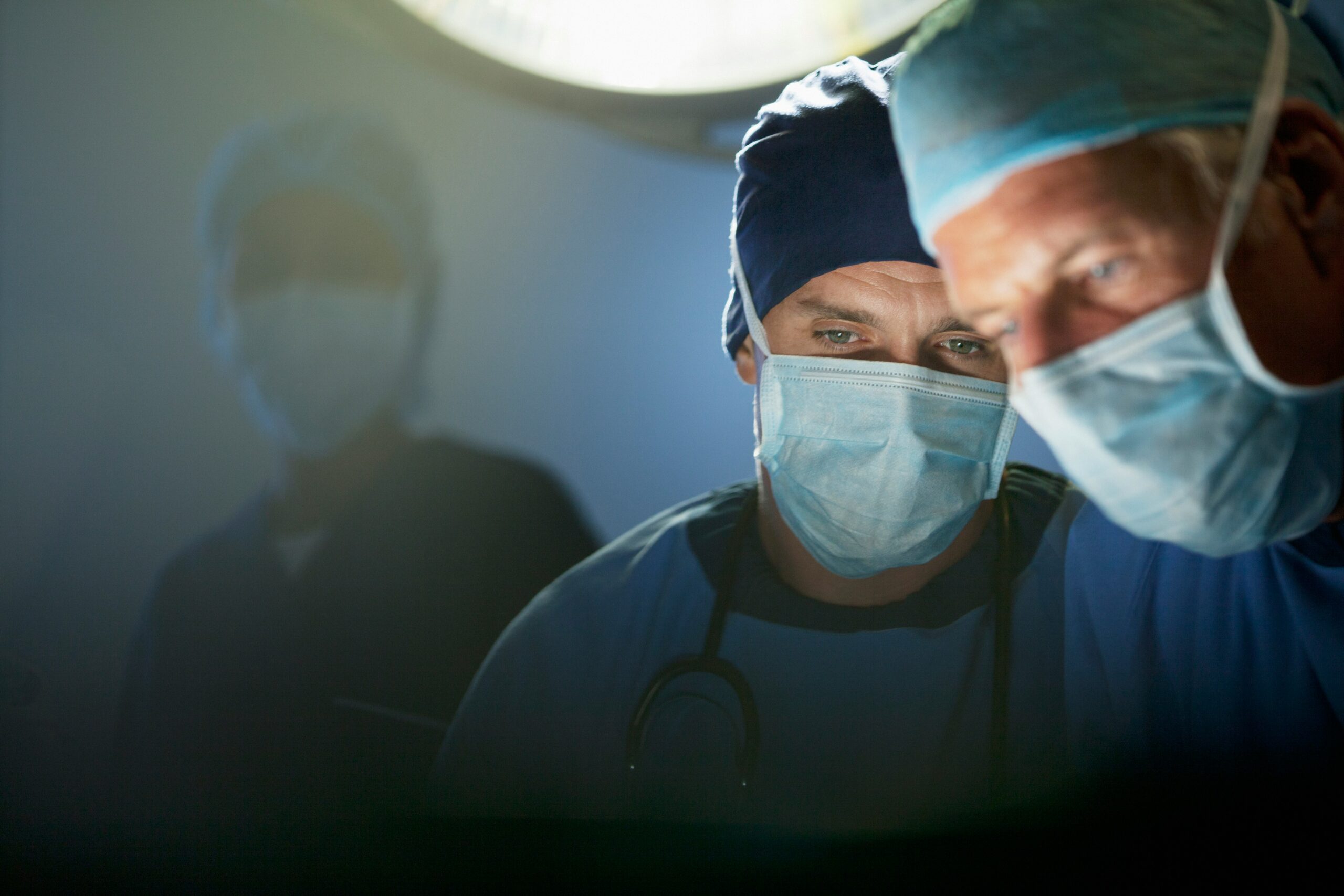 Two surgeons in scrubs examining a medical chart in a well-lit operating room.