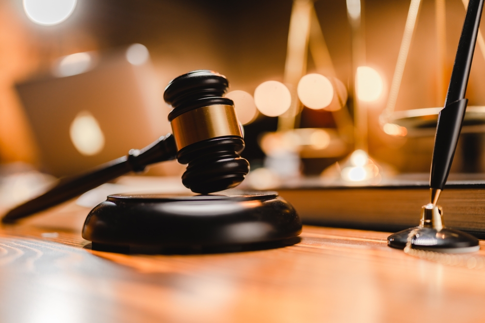 Judge's gavel resting beside law books on a polished wooden table, symbolizing legal authority and justice.