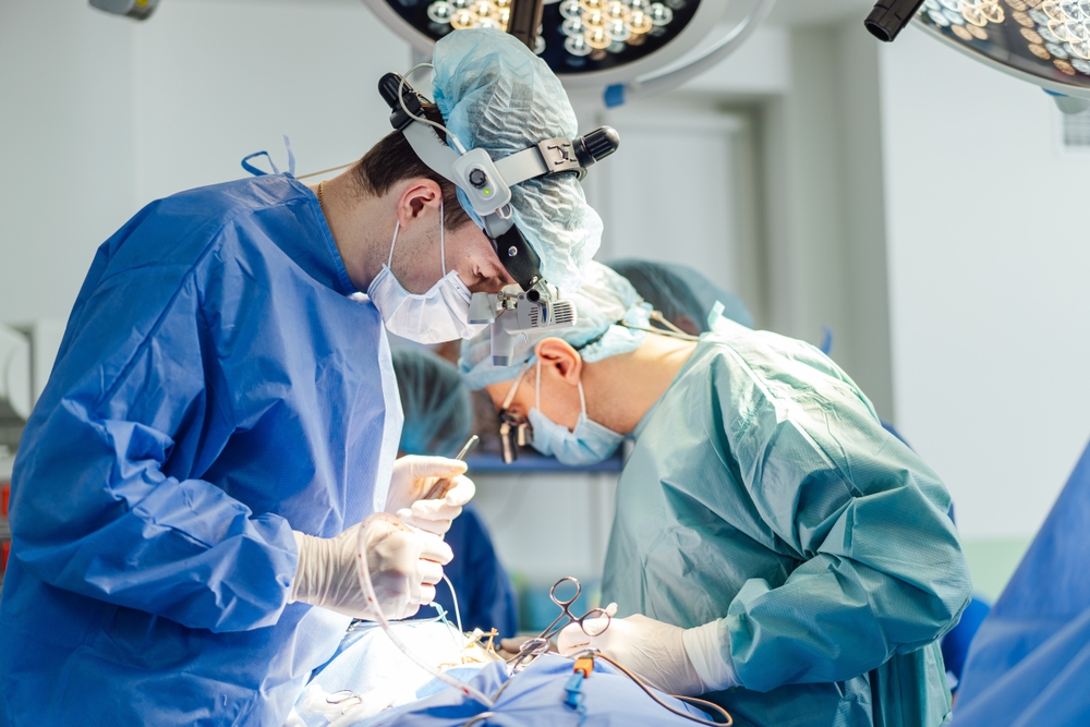 Two surgeons in blue scrubs focused on performing a surgical procedure in an operating room.