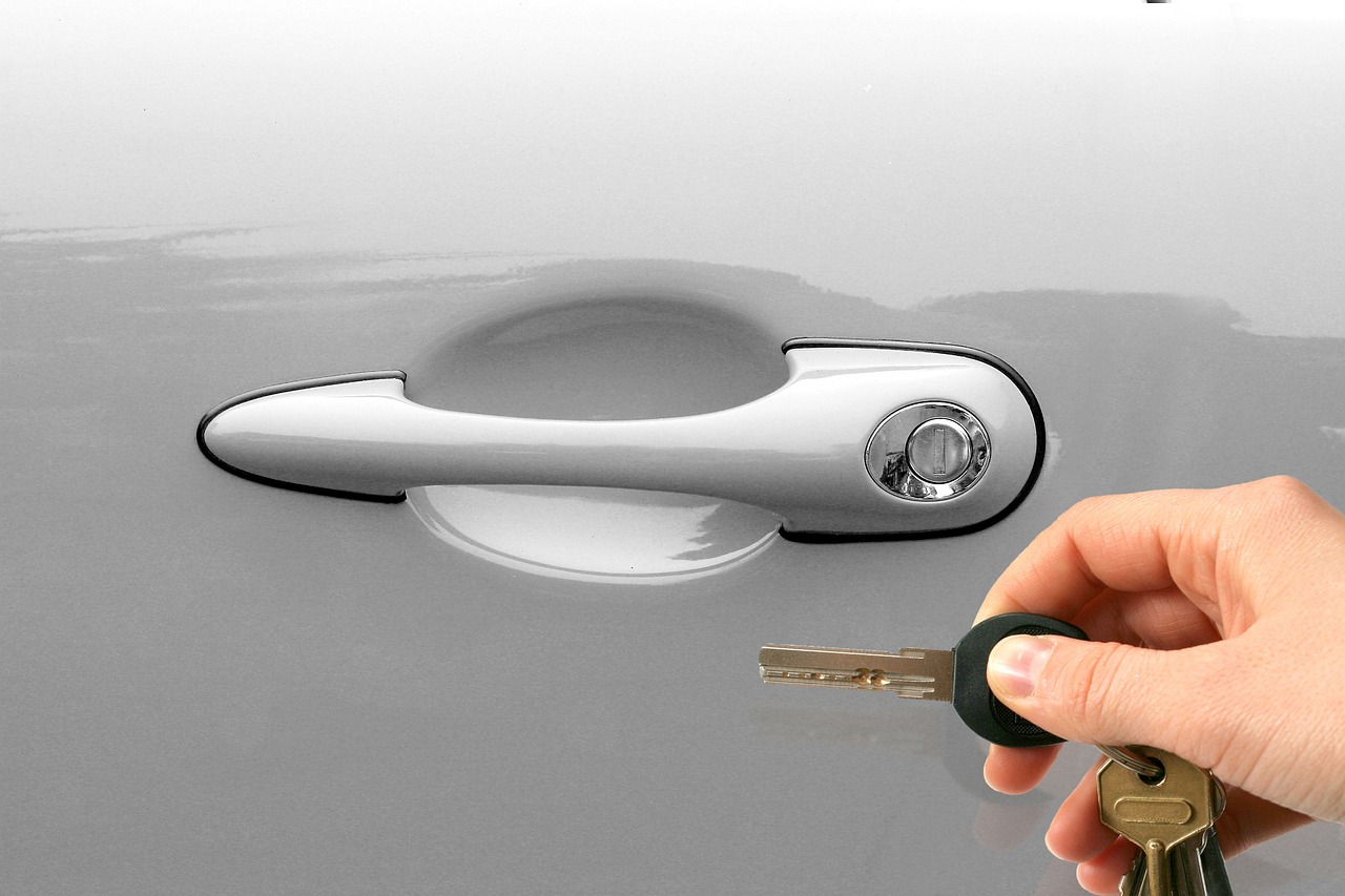  A person holding a key, poised to unlock a car door handle.