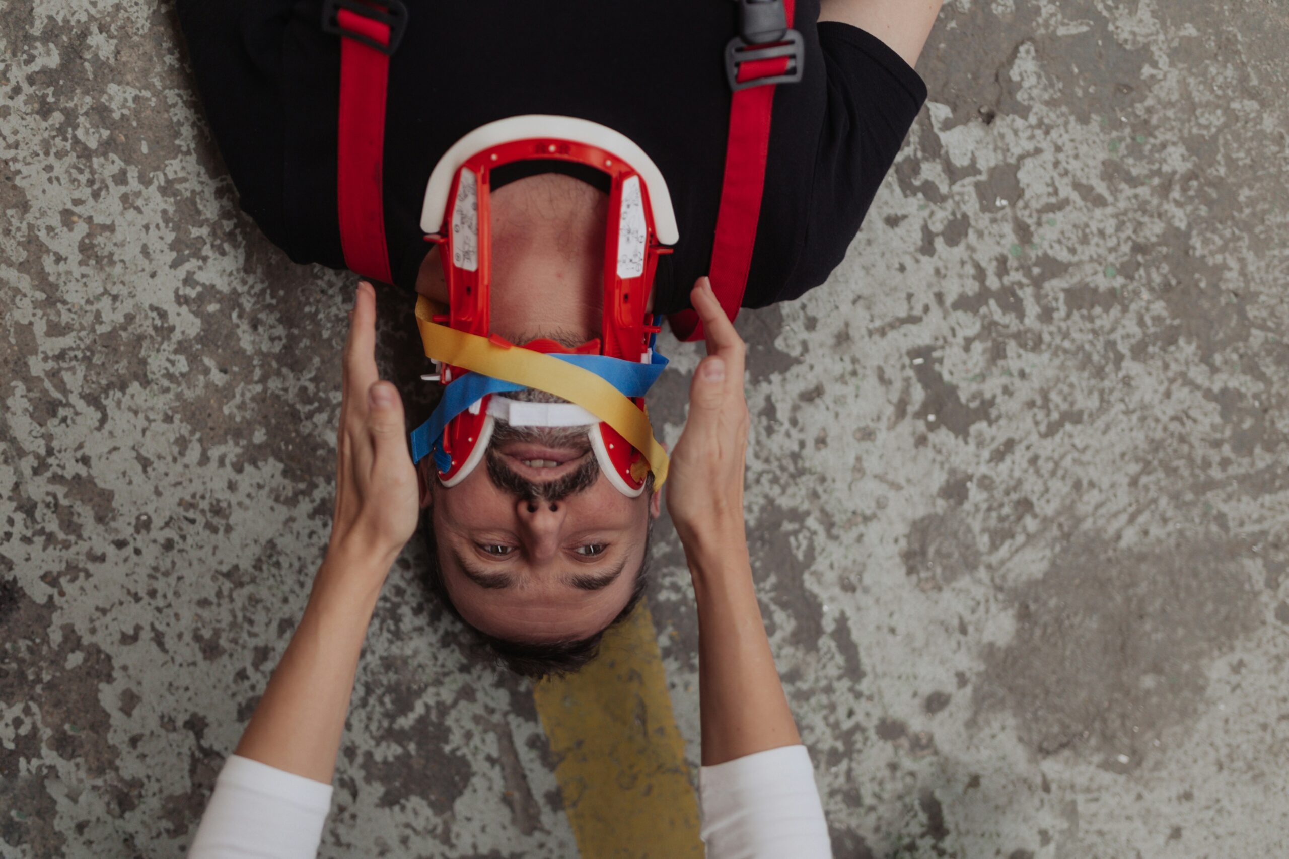 an injured man lies on the ground, wearing a neck brace