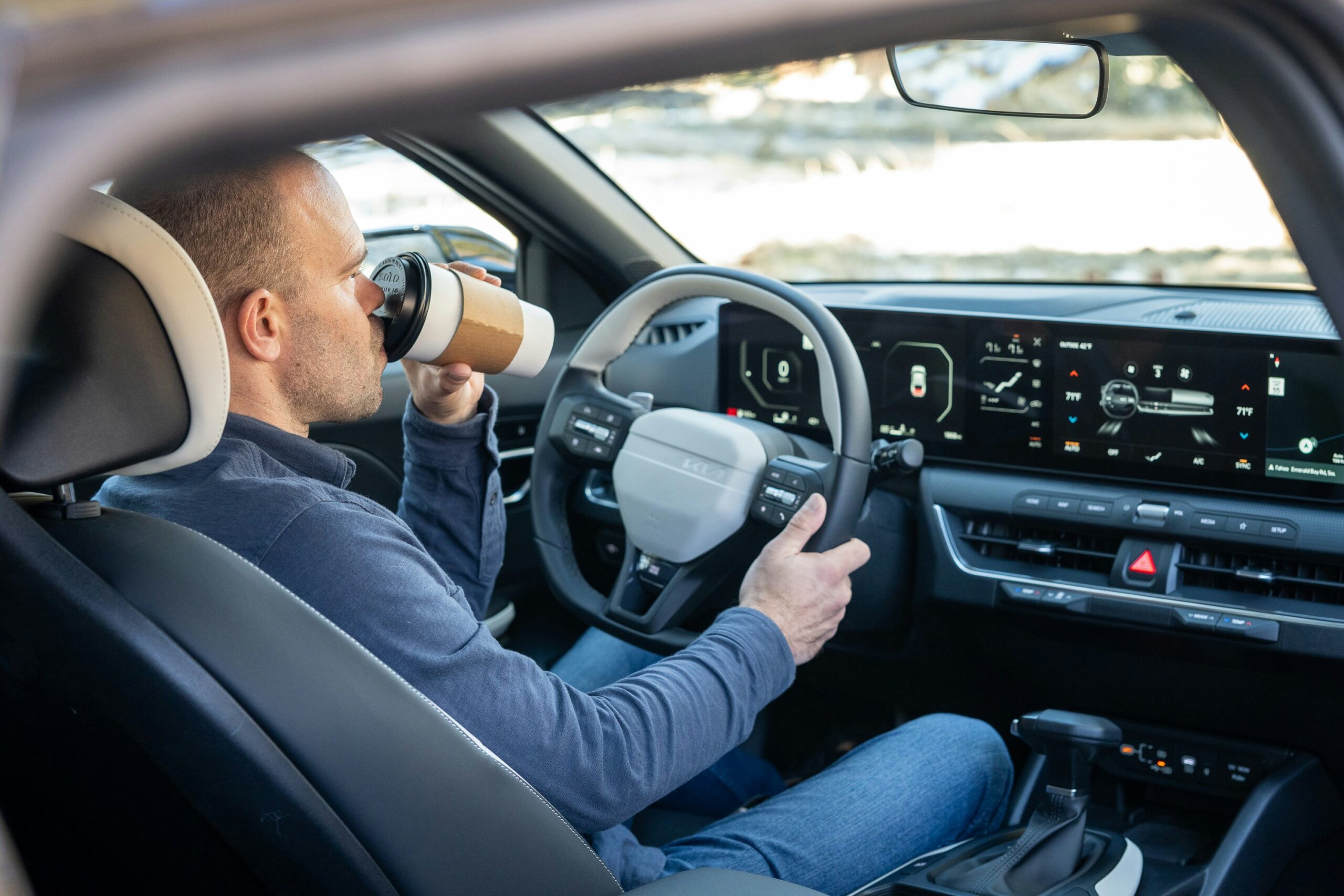 A male driver take a sip from a disposable coffee cup