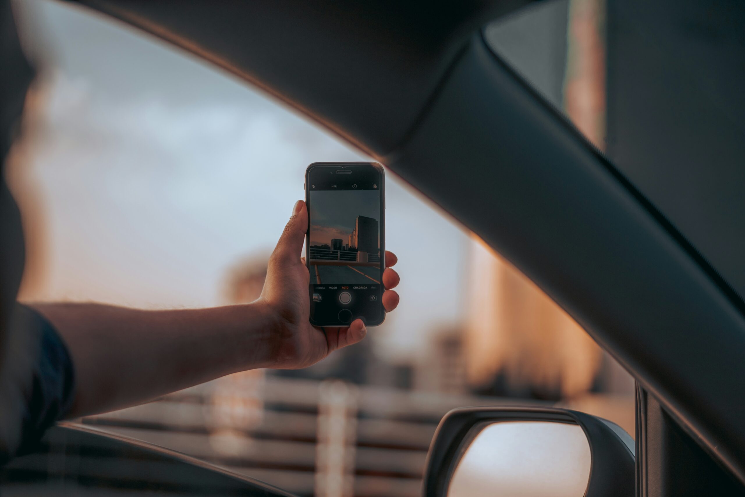 A distracted driver takes a photo of the city outside while the car is in motion