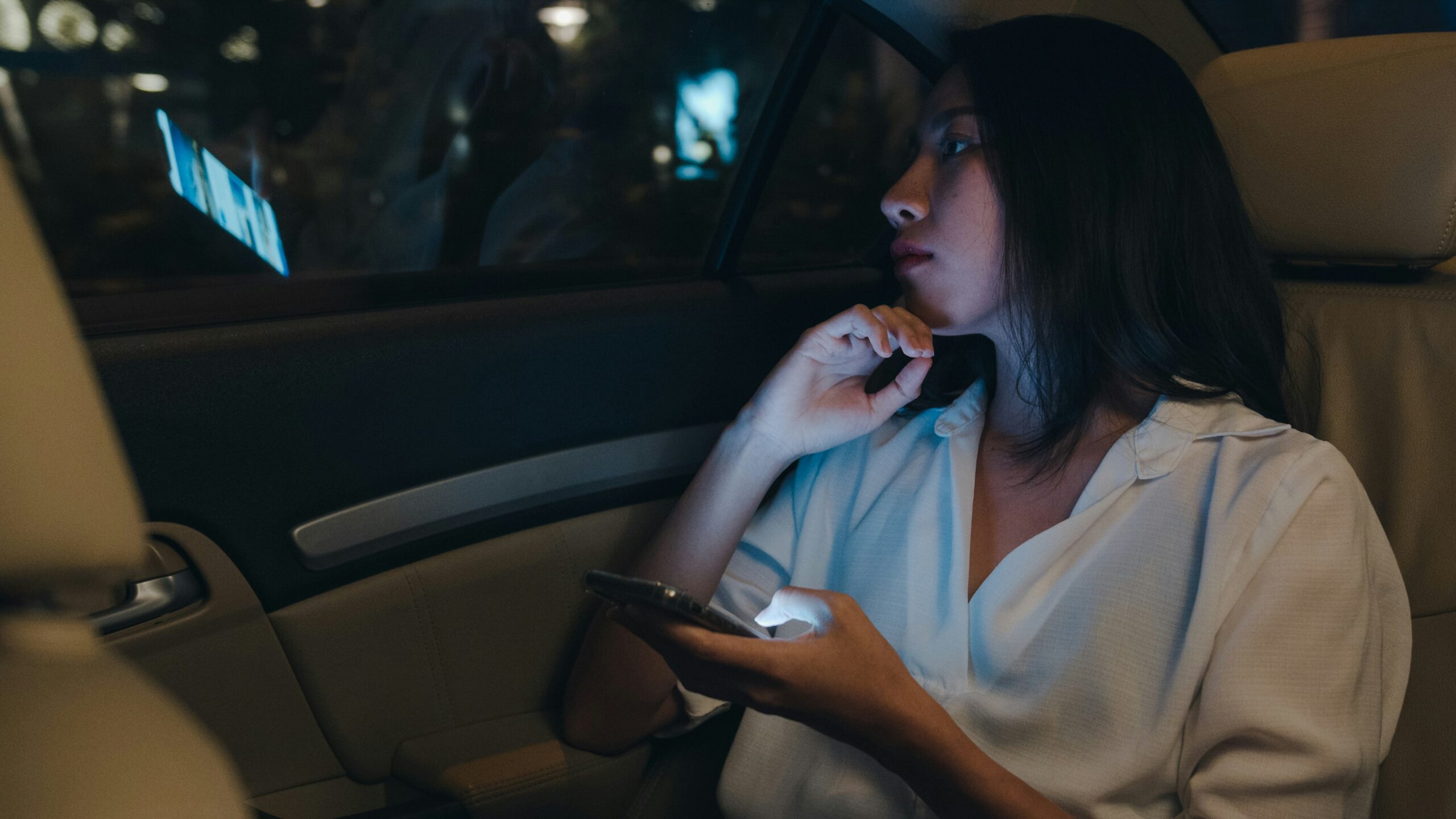 a woman looks out the back window of her Uber ride at night
