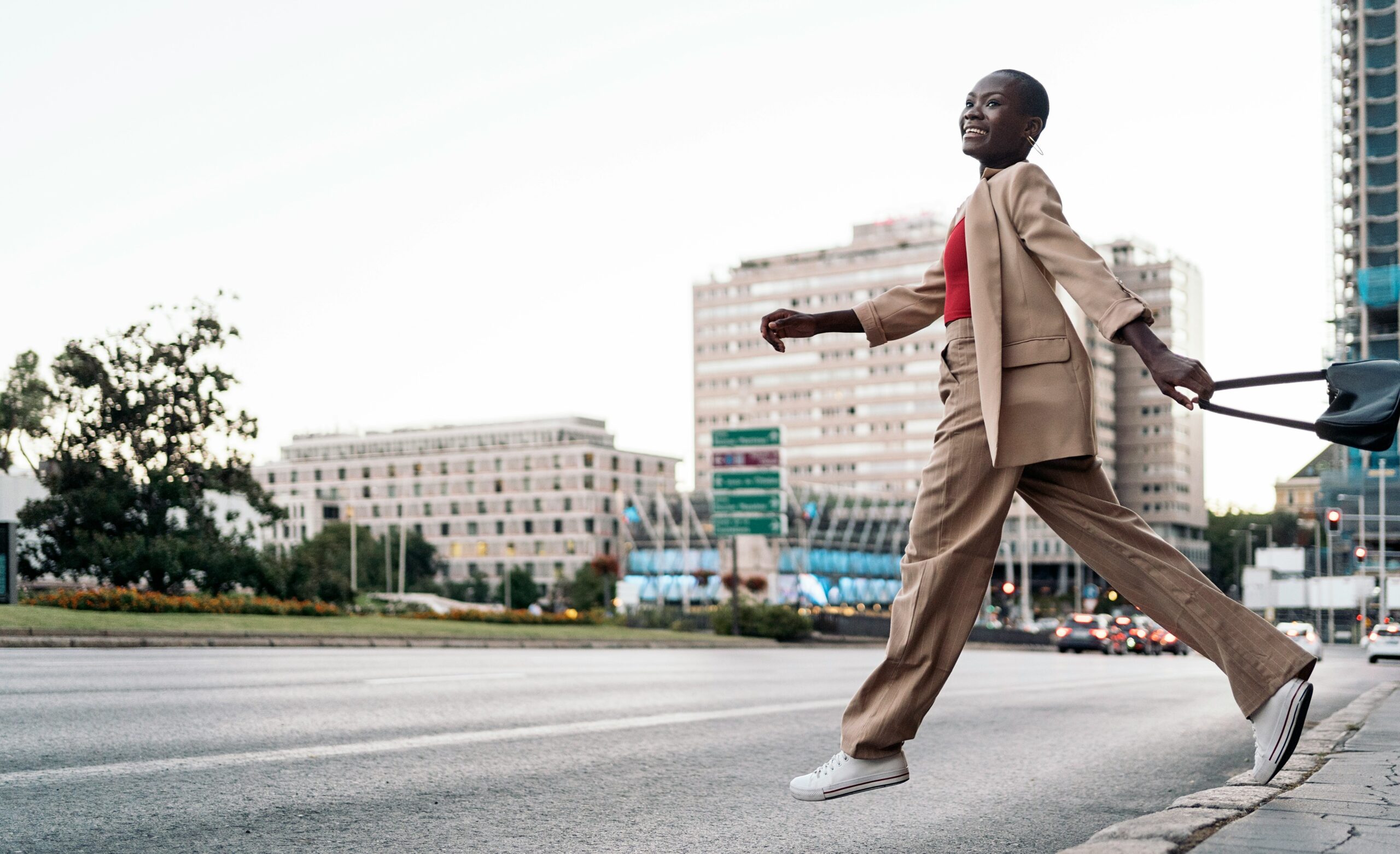 a happy looking woman steps into a street, outside of a crosswalk