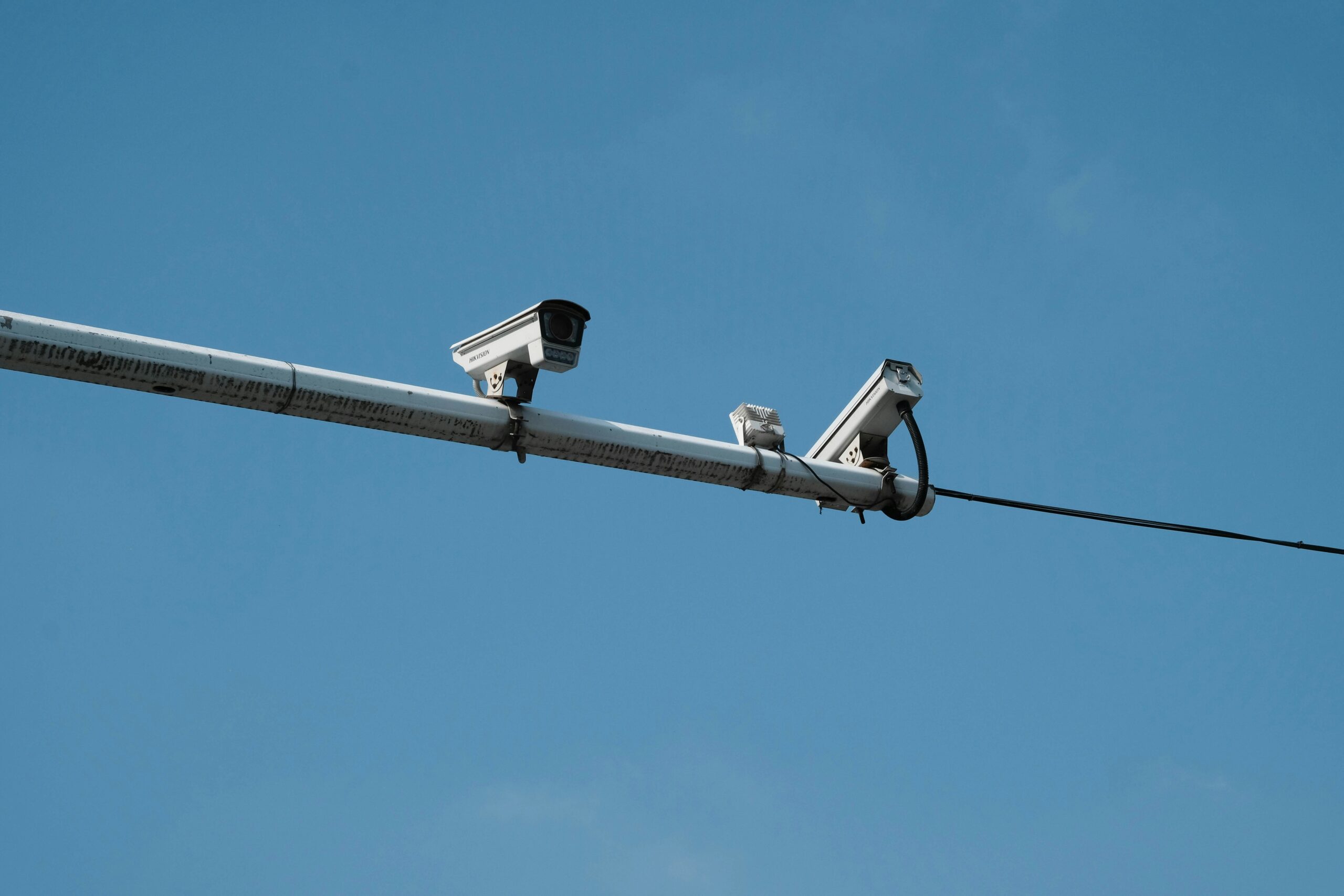 two traffic cameras on a fixture above a roadway
