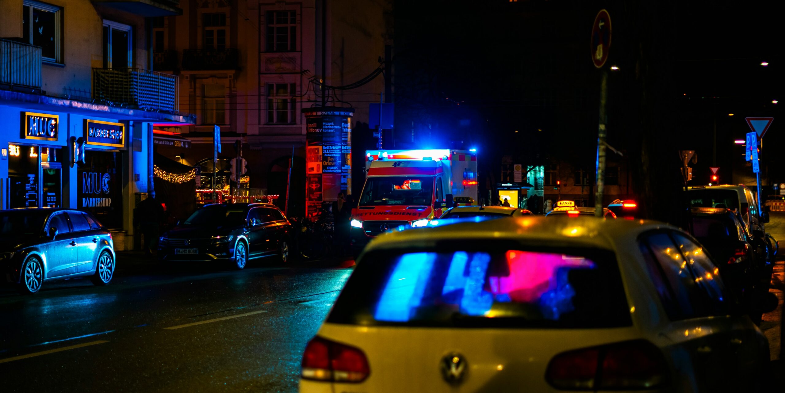 A car drives down a dimly lit street at night, with streetlights illuminating the surroundings.